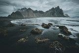 Mörka berg och svart sandstrand