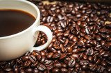 Närbild på kaffekopp och rostade bönor