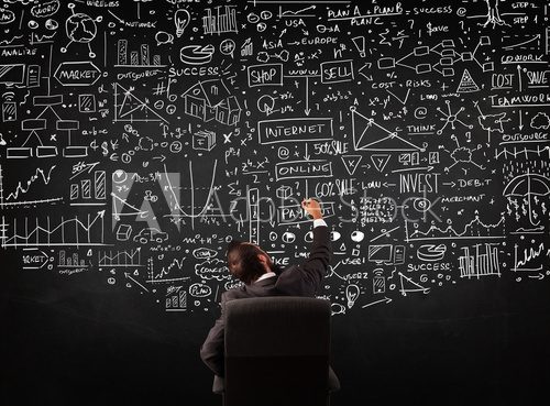 Businessman sitting in front of a blackboard with charts
