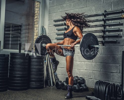 Female with barbell in a gym club.