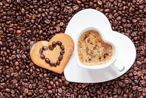 Heart shaped cup and cookie on coffee beans background