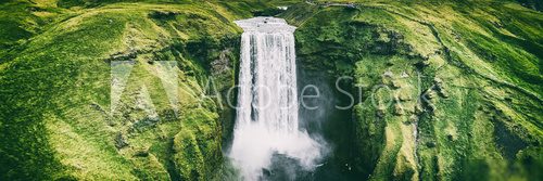 Iceland waterfall Skogafoss banner nature landscape. Panoramic destination in Icelandic famous world landmark tourist attraction on South Iceland. Aerial drone view of top waterfall.