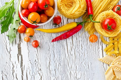 Mix of pasta, tomatoes and chili copy space wooden background