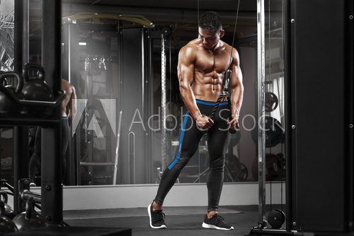 Muscular man working out in gym doing exercises at triceps, strong male naked torso abs