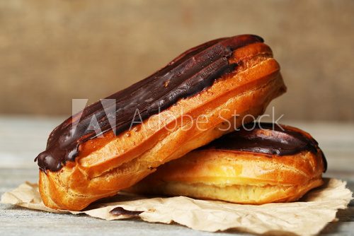 Tasty eclairs on wooden table, close up