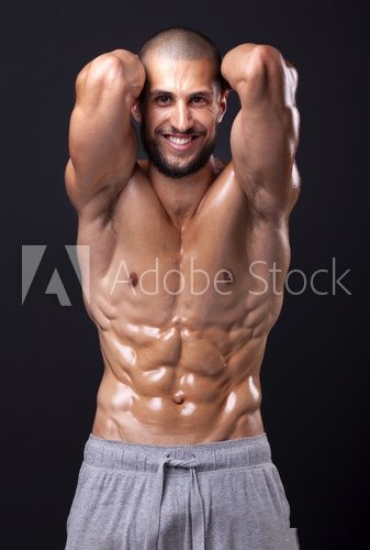 Smiling fit man flexing the abdominal on black background