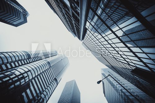 Looking up to high-rise office buildings, skyscrapers, architectures in financial district. Smart urban city for business and technology concept background in Downtown Hong Kong.